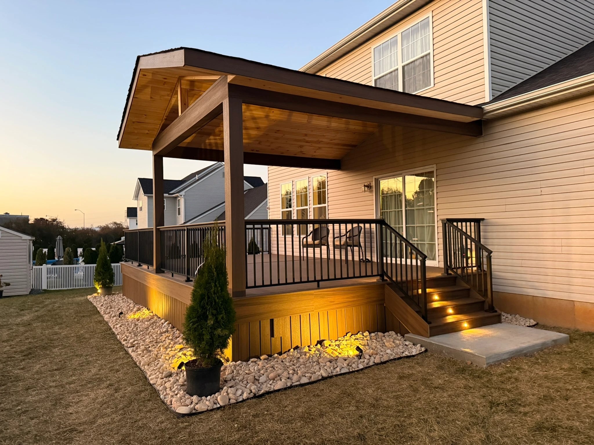 VM Power covered deck at sunset with a timber ceiling, black railing, and illuminated stairs