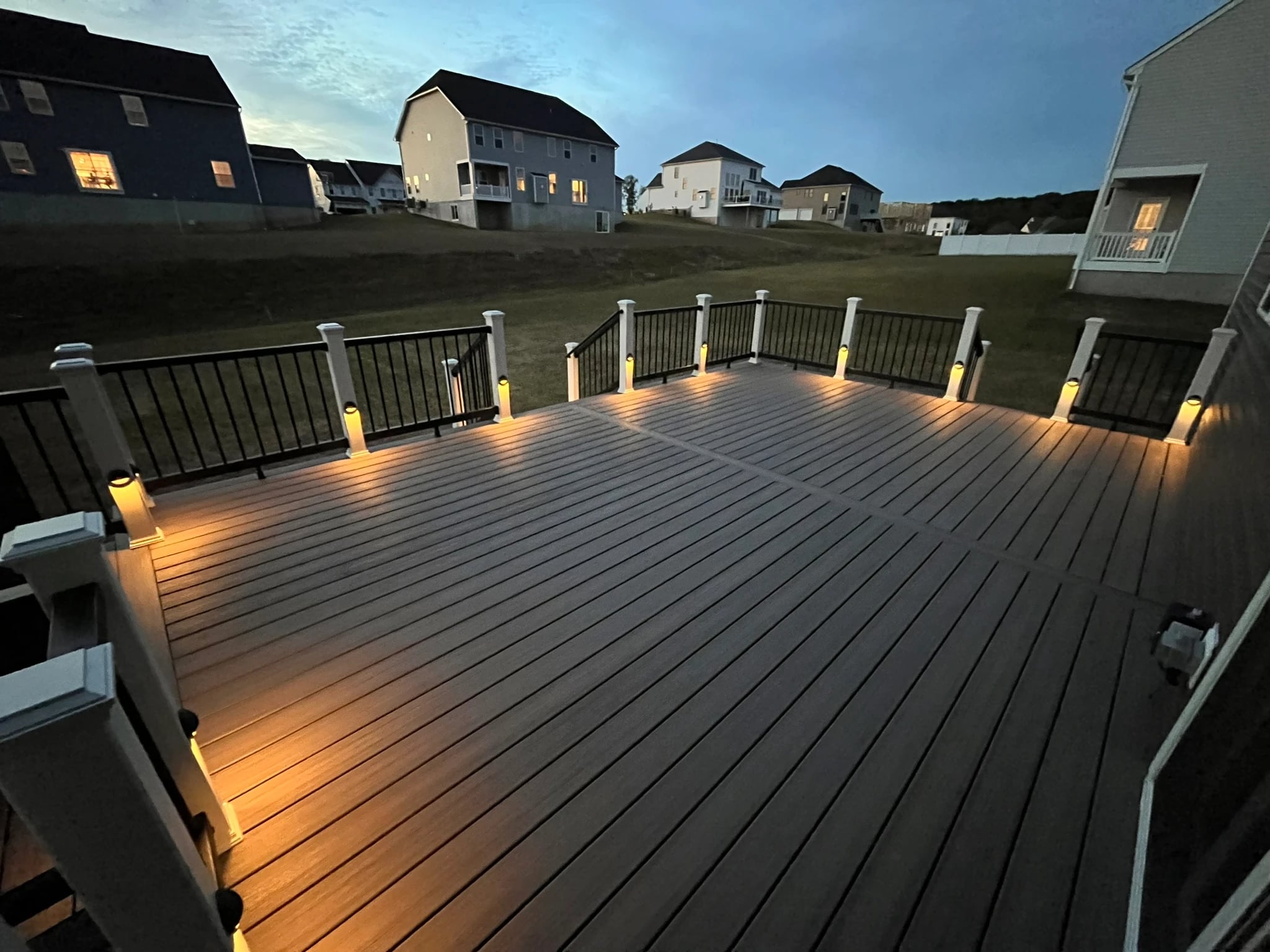 VM Power composite deck after dark with warm post lighting and black railing